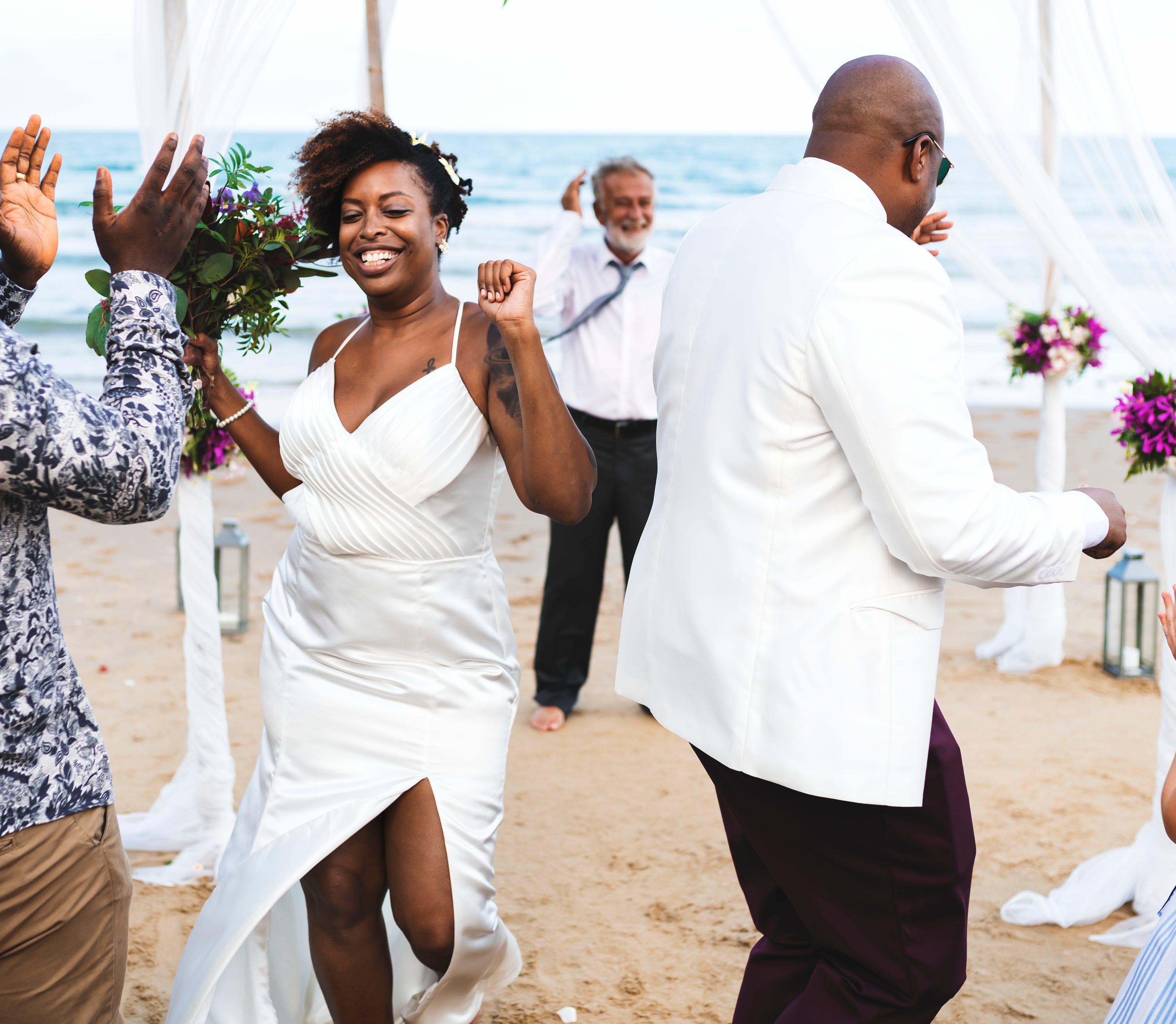Wedding couple celebrating on a beach with family and friends, wedding video production.